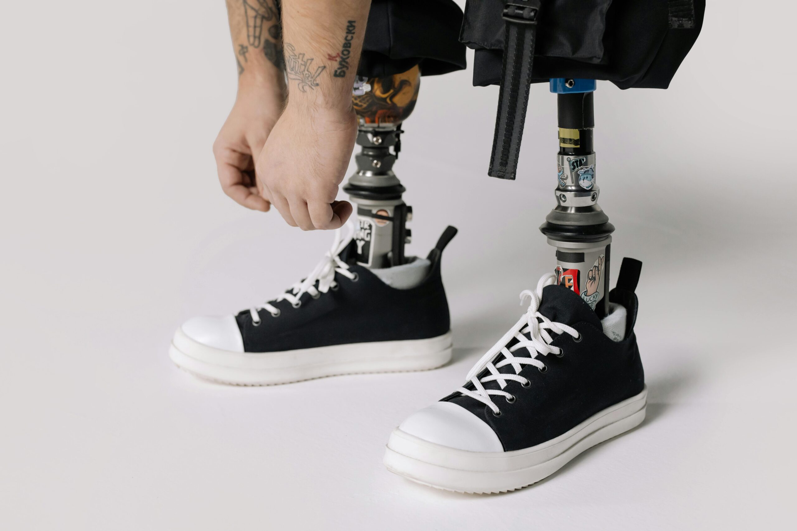 Close-up of a man tying shoelaces on sneakers attached to prosthetic legs.