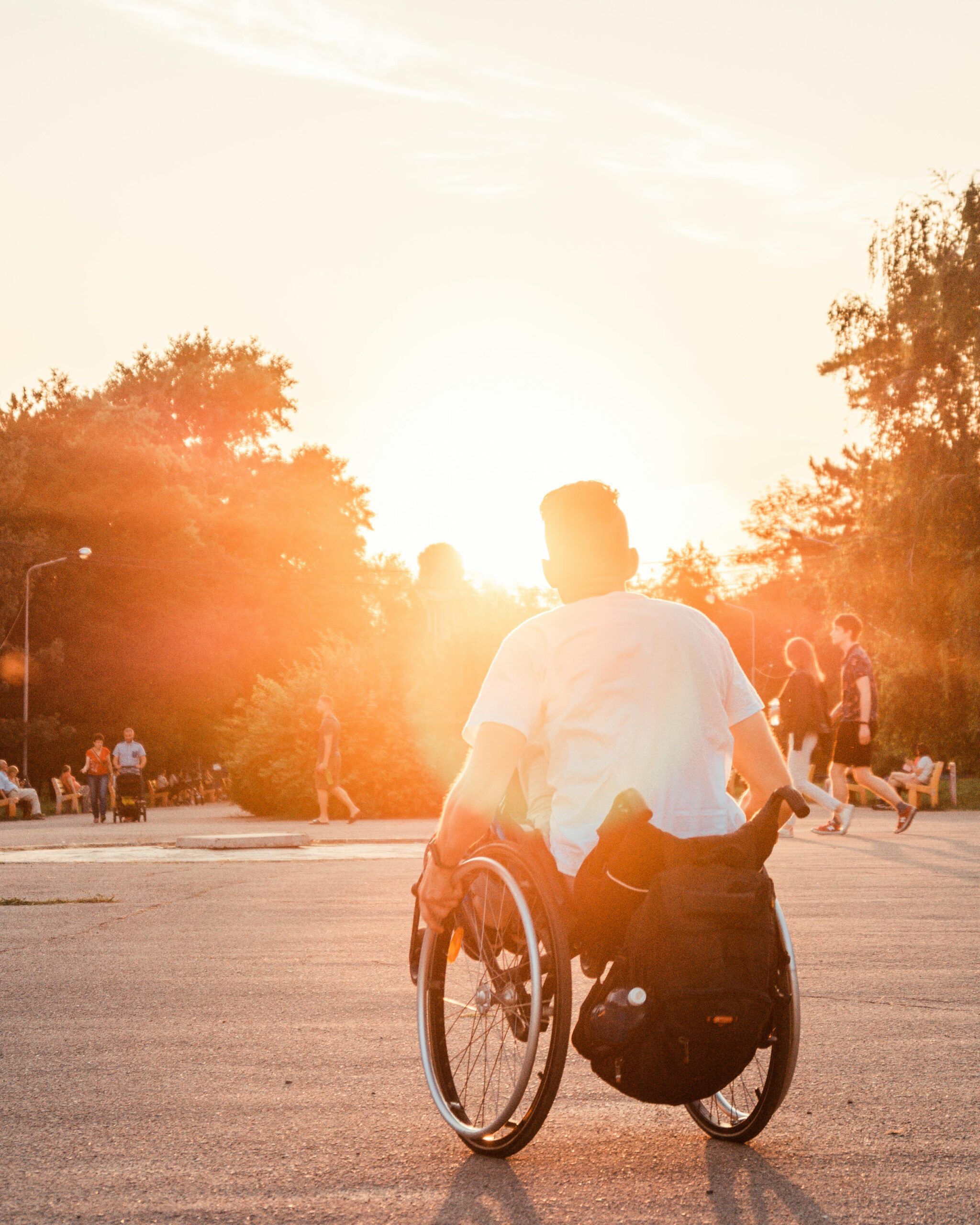 Man in a wheelchair basking in the warm sunset outdoors, symbolizing freedom and accessibility.